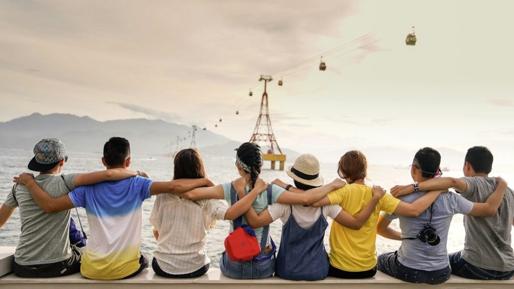 Group of friends sitting together arm in arm, seen from behind